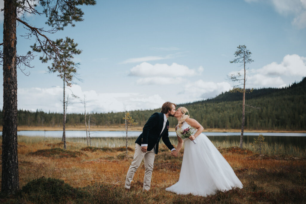 Brudpar kysser varandra på deras bröllop vid tjärnen på Tännäskröket
