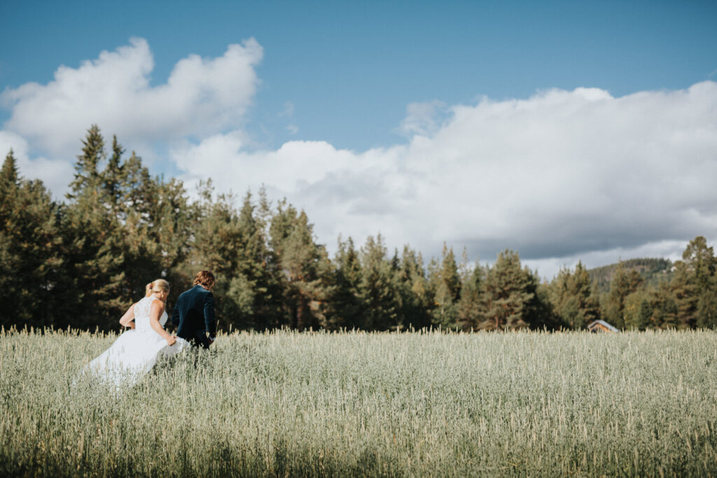 Brudpar går över fält under sitt bröllop i Funäsfjällen